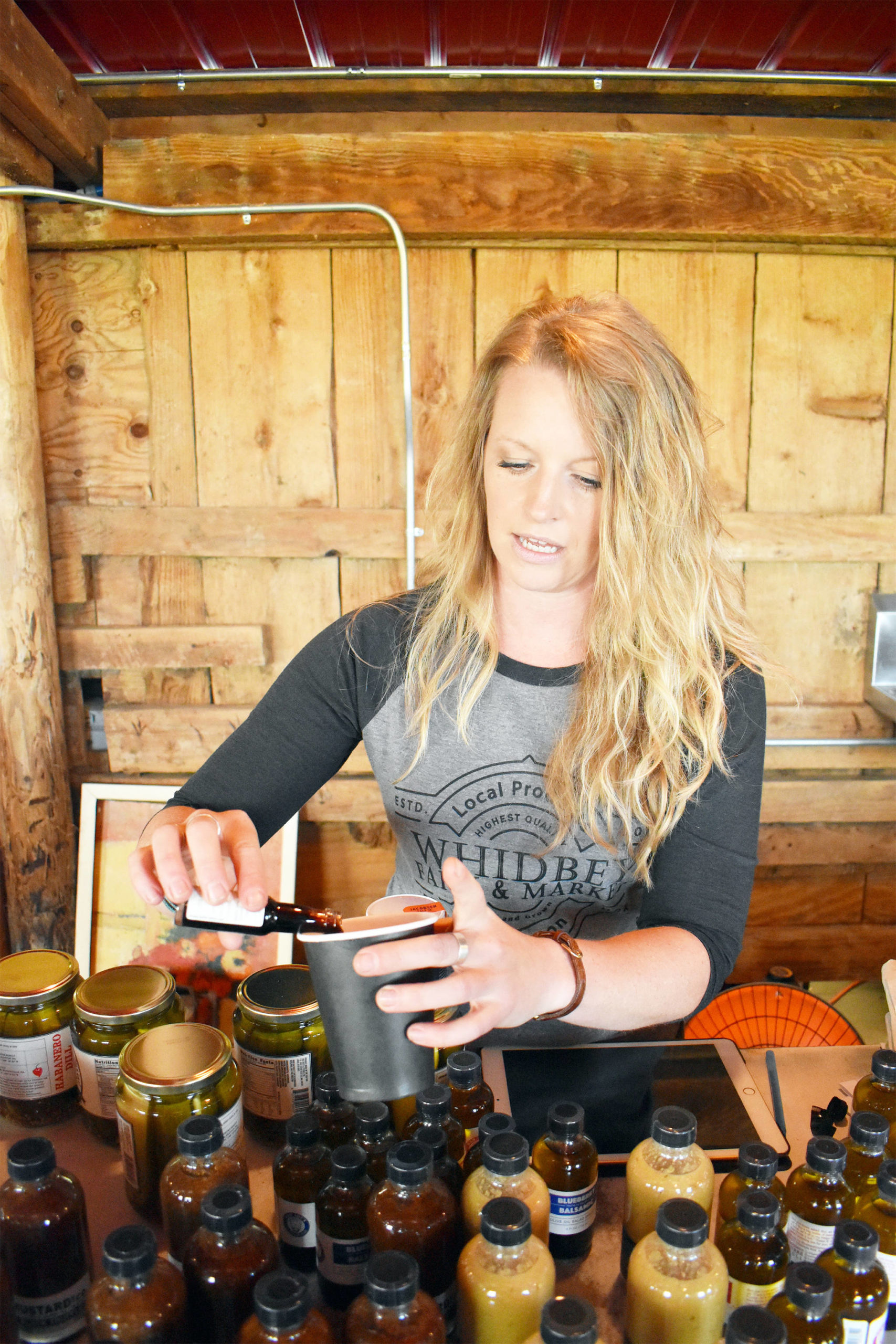 Market co-owner Shannon Hamilton pours a sample of drinking vinegar. Photo by Emily Gilbert/Whidbey News-Times