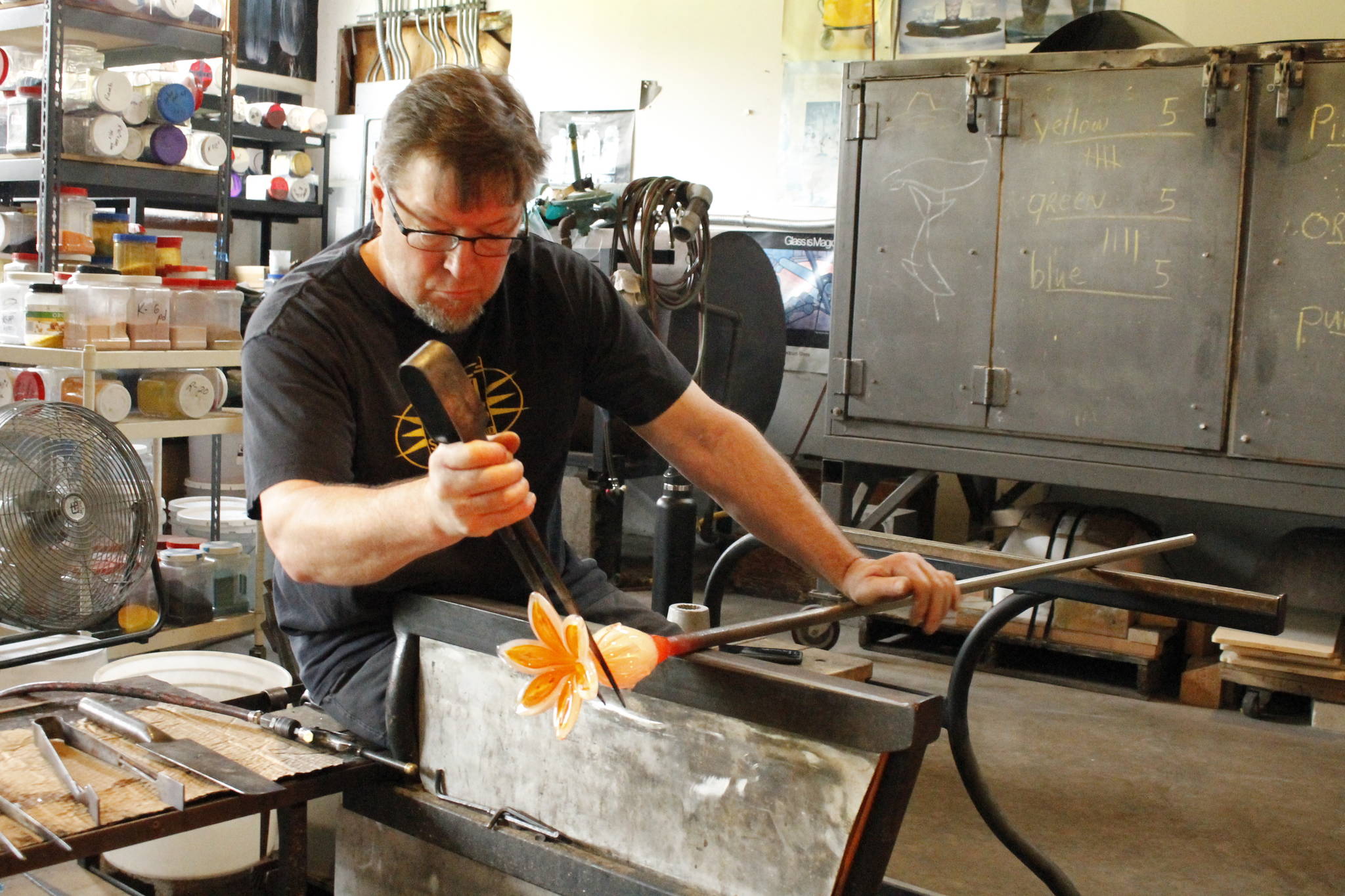 Eric Leiberman of Island Art Glass shapes a glass-blown lily using a large pair of tweezers. (Photo by Kira Erickson/South Whidbey Record)