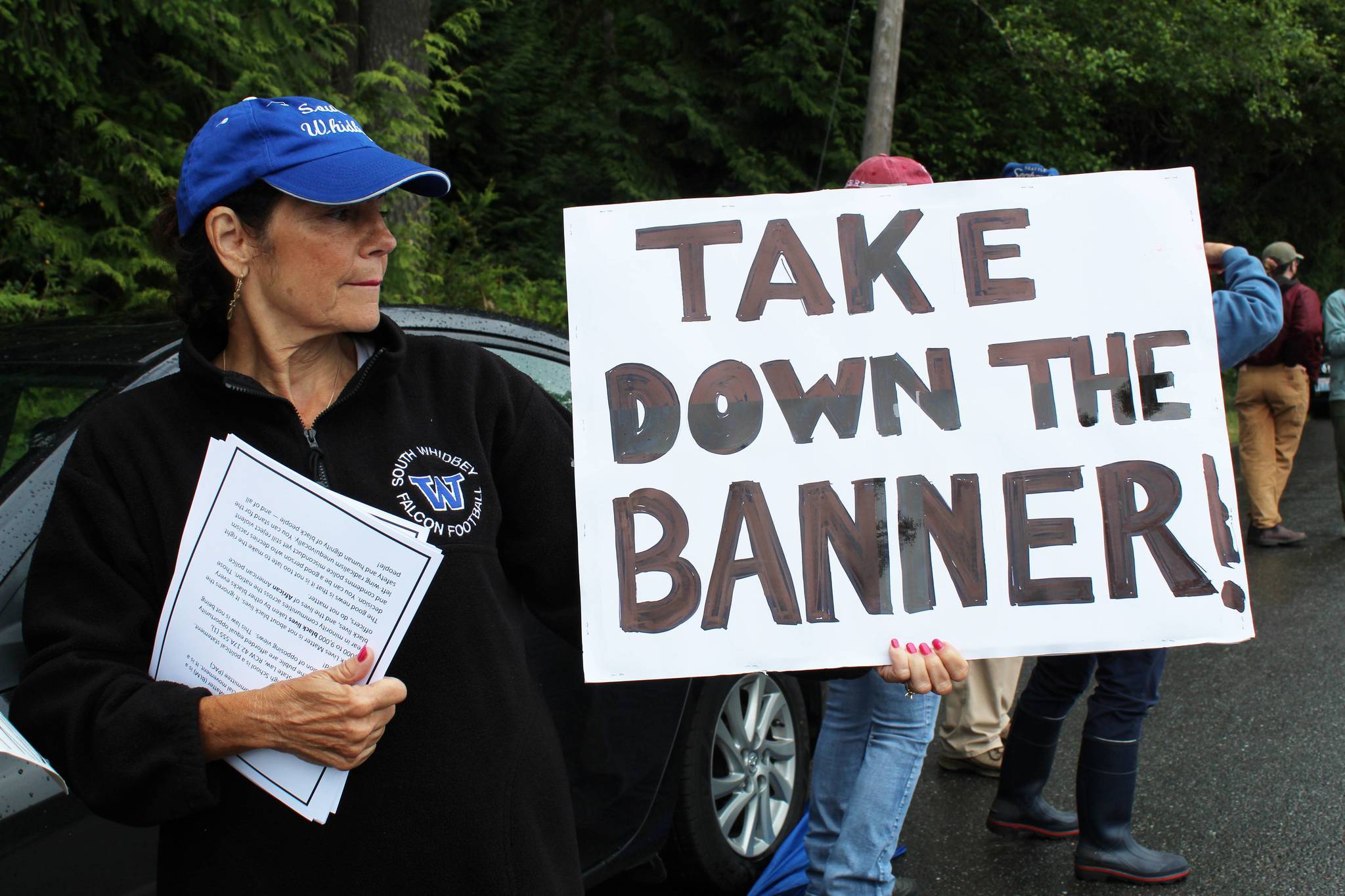 Maureen Greene displays a sign and distributes informational papers opposing the Black Lives Matter banner at the June 11 protest. (Photo by Karina Andrew/Whidbey News-Times)