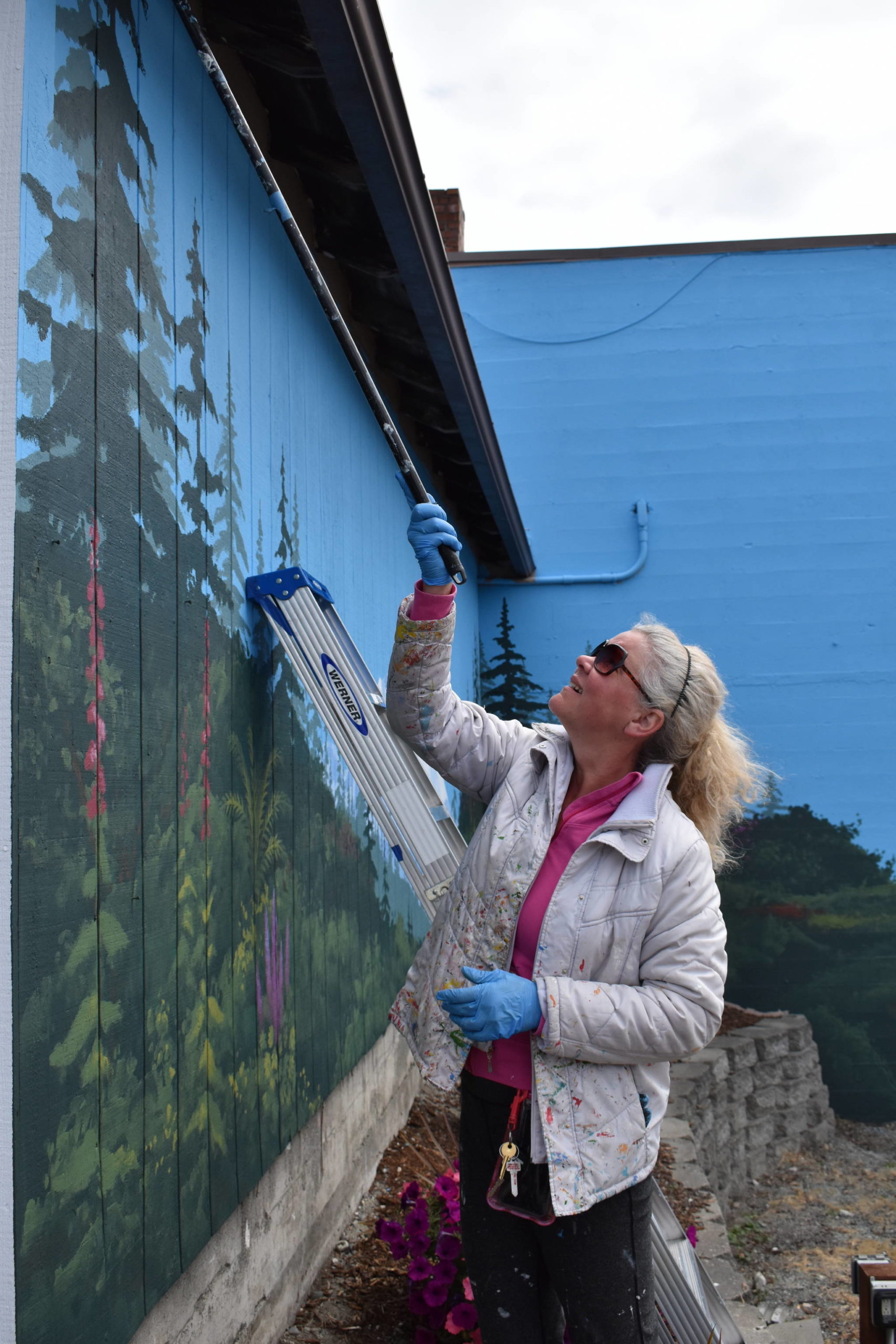 Photo by Emily Gilbert/Whidbey News-Times Paula Fries working on a mural on the corner of Southeast Dock Street and Southeast Pioneer Way in downtown Oak Harbor. The mural spans two walls and features Mount Baker, rolling hills and a soon-to-be gate to a secret garden.
Photo by Emily Gilbert/Whidbey News-Times Paula Fries working on a mural on the corner of Southeast Dock Street and Southeast Pioneer Way in downtown Oak Harbor. The mural spans two walls and features Mount Baker, rolling hills and a soon-to-be gate to a secret garden.