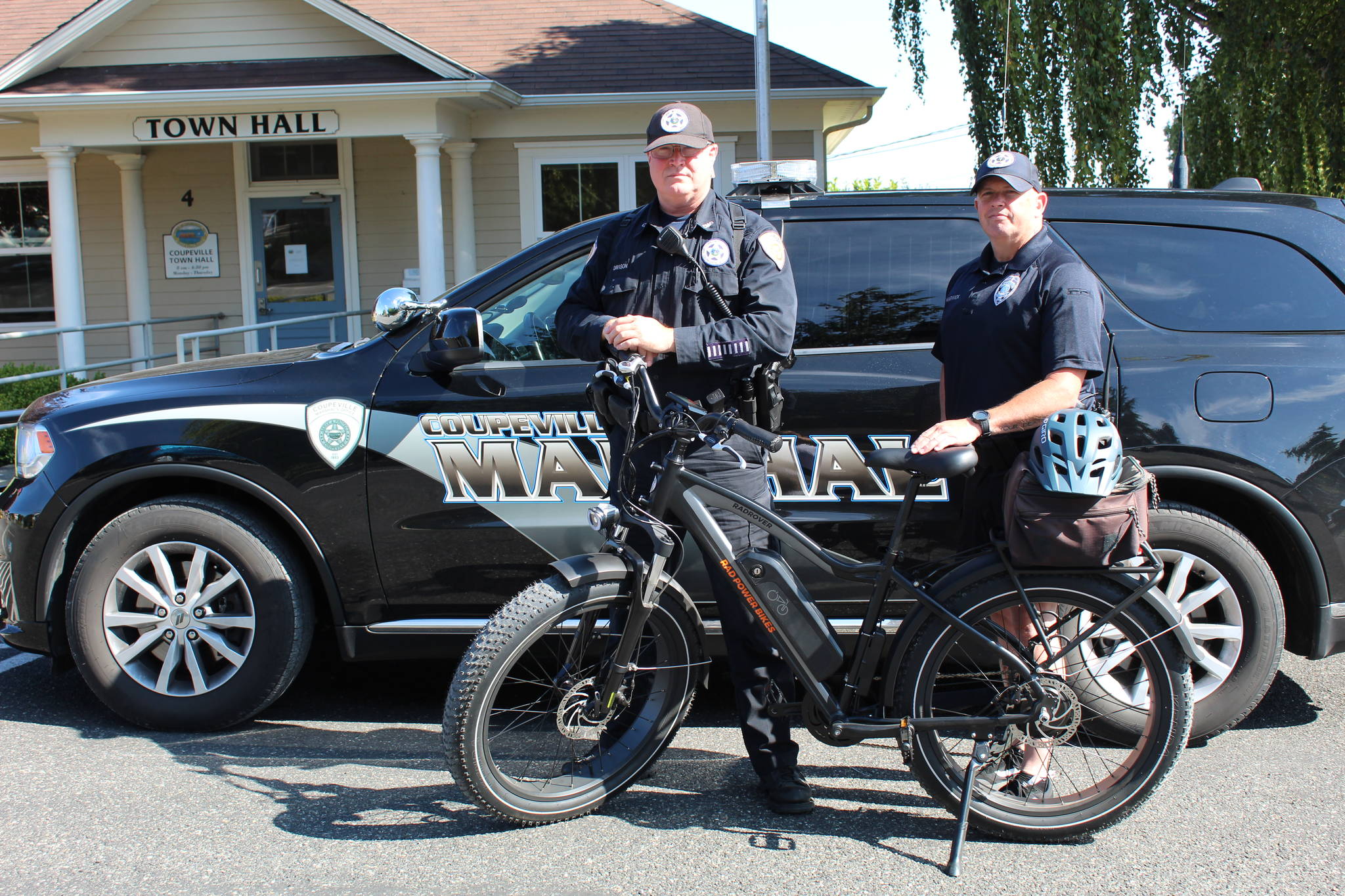 Officers Shawn Warwick, right, and Rob Davison stand with their new police e-bike. The bike allows them to interact with Coupeville residents more easily. (Karina Andrew/Whidbey News-Times)