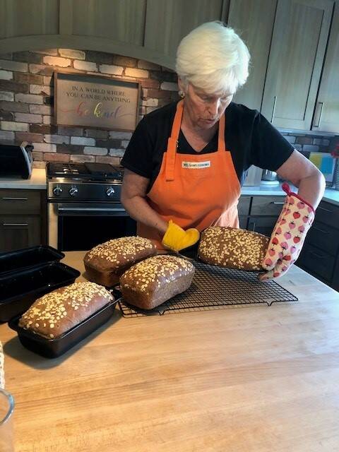 Photo provided
Sue Mills, the volunteer coordinator of the South Whidbey hub for Community Loaves, with four finished loaves of honey oat, whole grain bread.