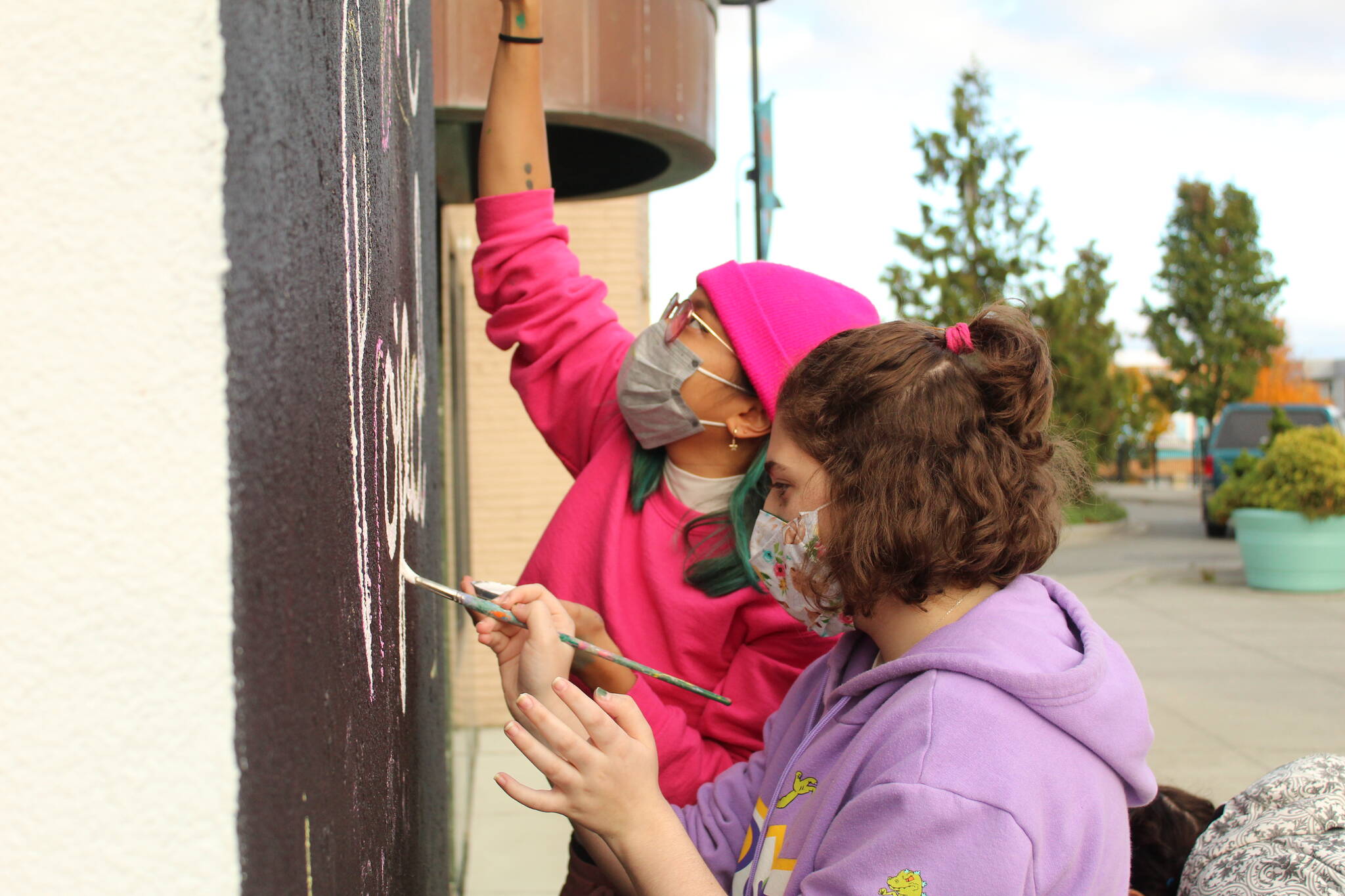 Photo by Karina Andrew/Whidbey News-Times
Oak Harbor High School junior Kaydence Murdock, front, and artist Nikita Ares paint the wall where the next Allgire Project mural will go.