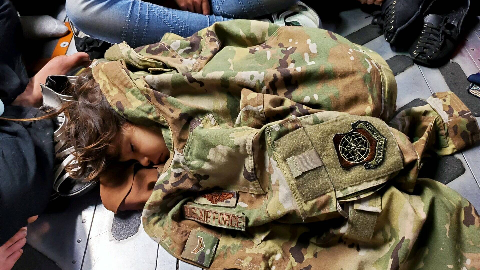 U.S. Air Force Photo
An Afghan child sleeps on the cargo floor of a U.S. Air Force C-17 Globemaster III, kept warm by the uniform of the C-17 loadmaster during an evacuation flight from Kabul, Afghanistan, Aug. 15, 2021.