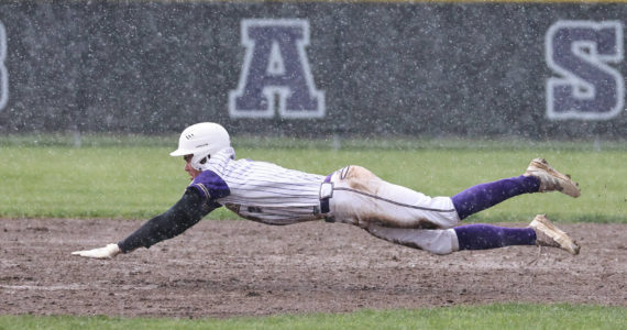 Photo by John Fisken
Oak Harbor High School baseball player Gage McLeod dives for the base during a rainy game against Anacortes April 4. Despite adverse weather conditions, the Wildcats were victorious.
