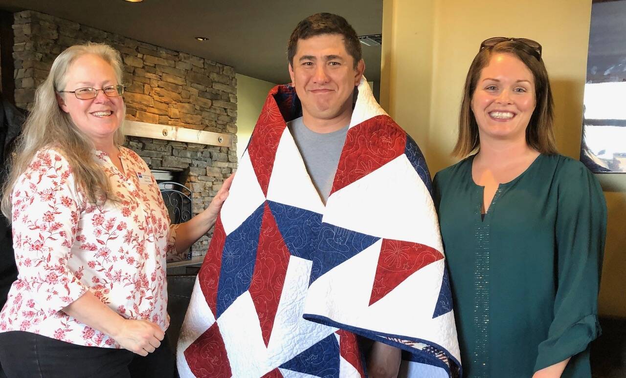 Photo by Harry Anderson
<em>Colleen Jones, left,and Tanya Gardner congratulate William Carroll on his new quilt.</em>
