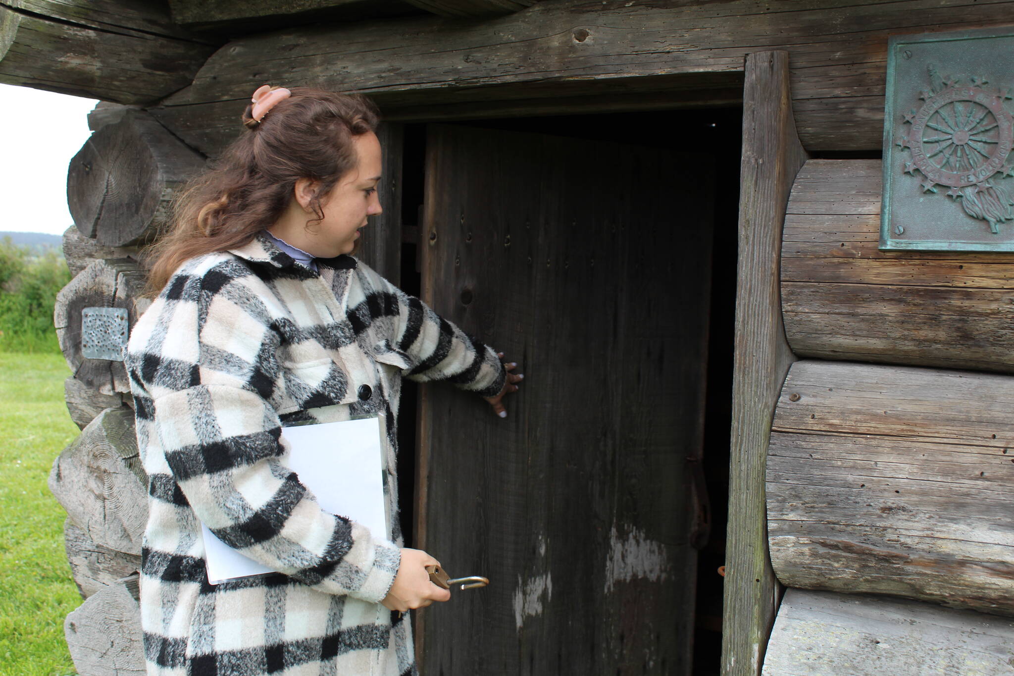 Reserve education and outreach coordinator Jordan Belcher opens the door of the blockhouse next to the Jacob and Sarah Ebey House. (Photo by Karina Andrew/Whidbey News-Times)