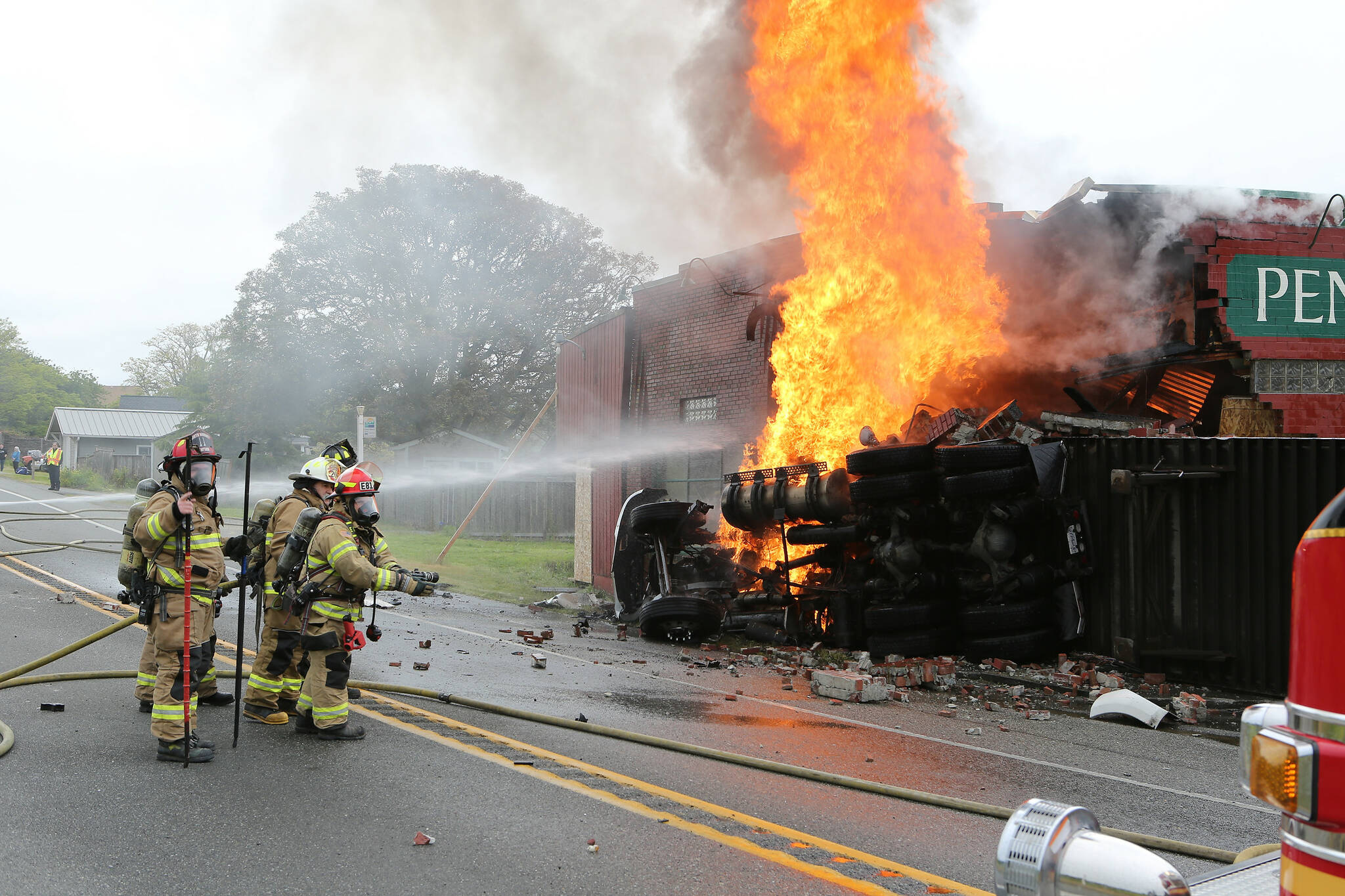 Photo by John Fisken
North Whidbey Fire and Rescue firefighters battle a blaze at Penn Cove Pottery after a semi truck crashed into the historic building Sunday morning.