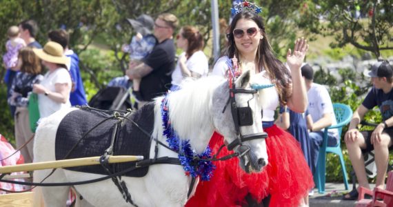 A woman particpating in the Fourth of July parade in Oak Harbor walks alongside a horse.