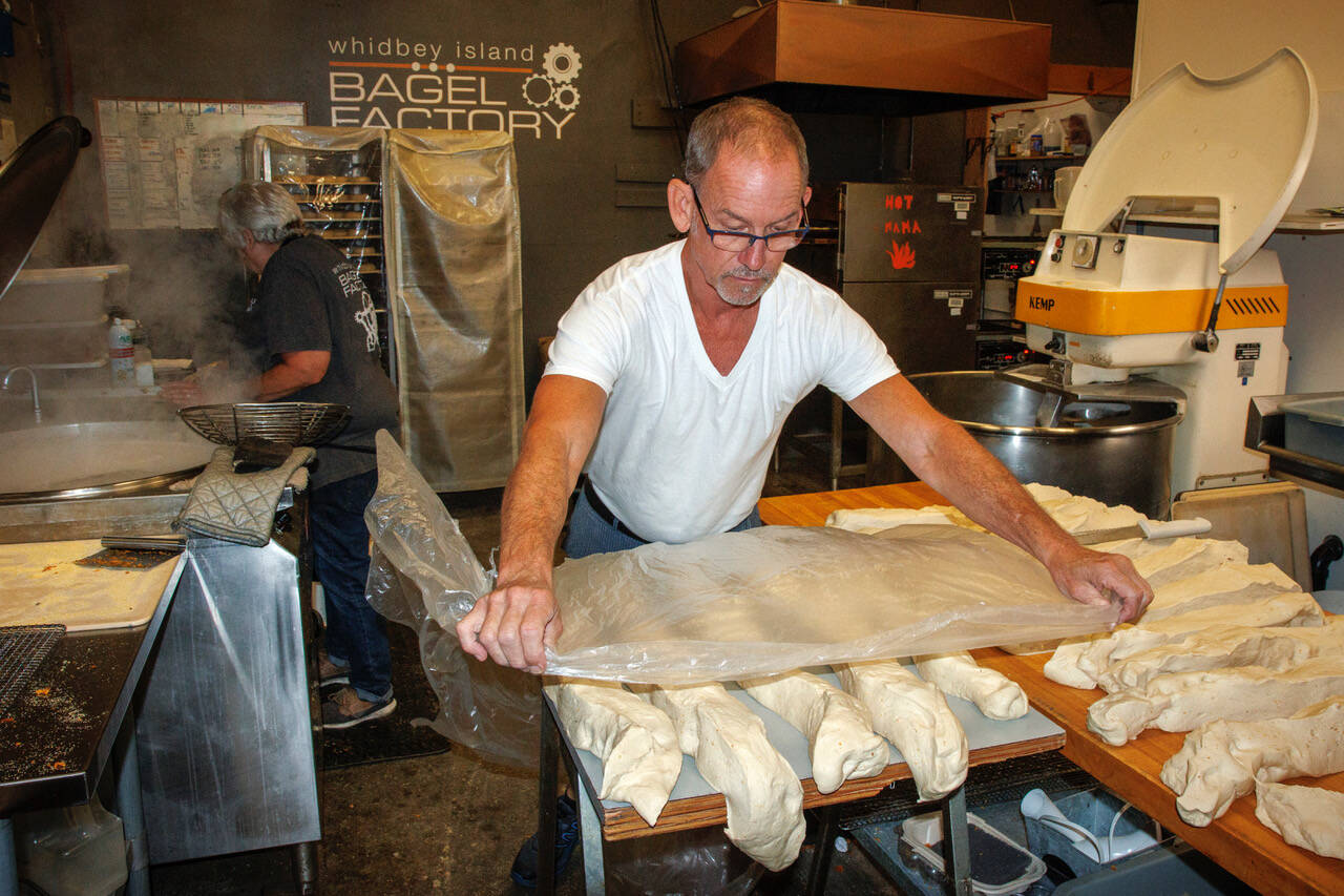 John Auburn cuts and shapes bagels. In the back, Carol Forgas boils them. (Photo by David Welton)