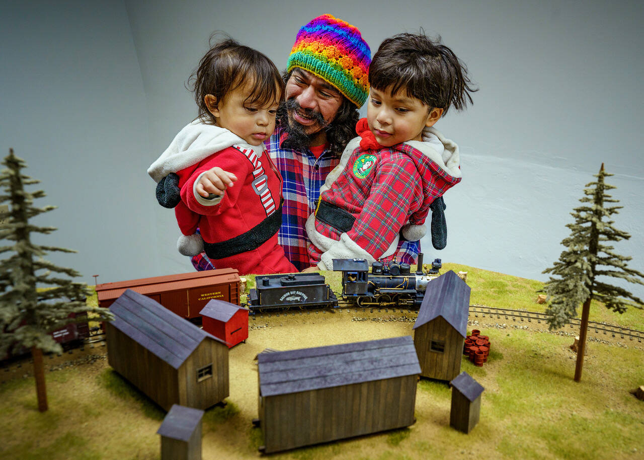 Photo by David Welton
Christian Gonzalez with Raphael, 2, and Zeke, 3, watch a model train in action.