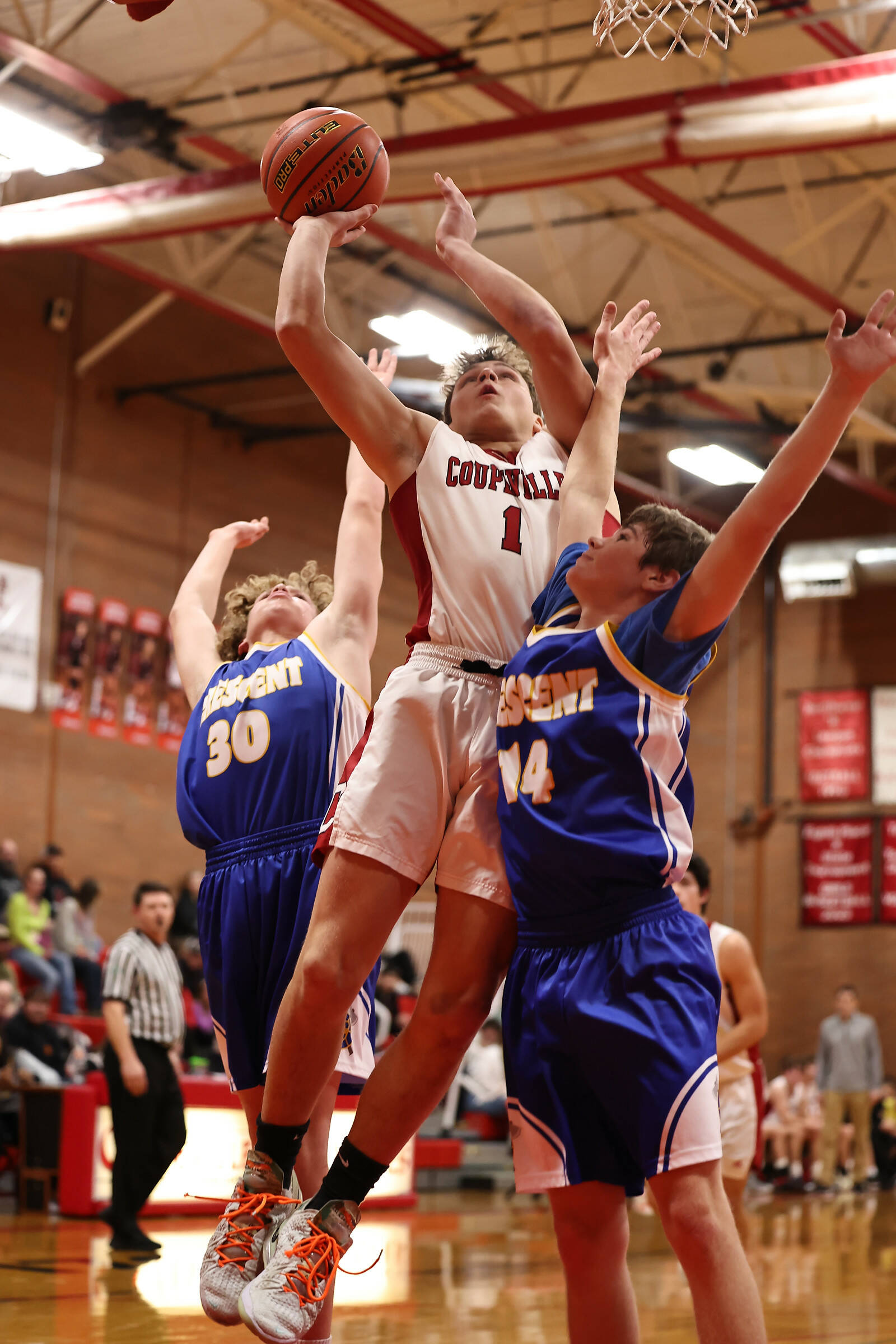 Photo by John Fisken
Coupeville High School senior Dominic Coffman shoots amid pressure from opposing Crescent players during a game at home Wednesday night. The boys team beat Crescent 60-14, ending the opponent’s previously undefeated season.