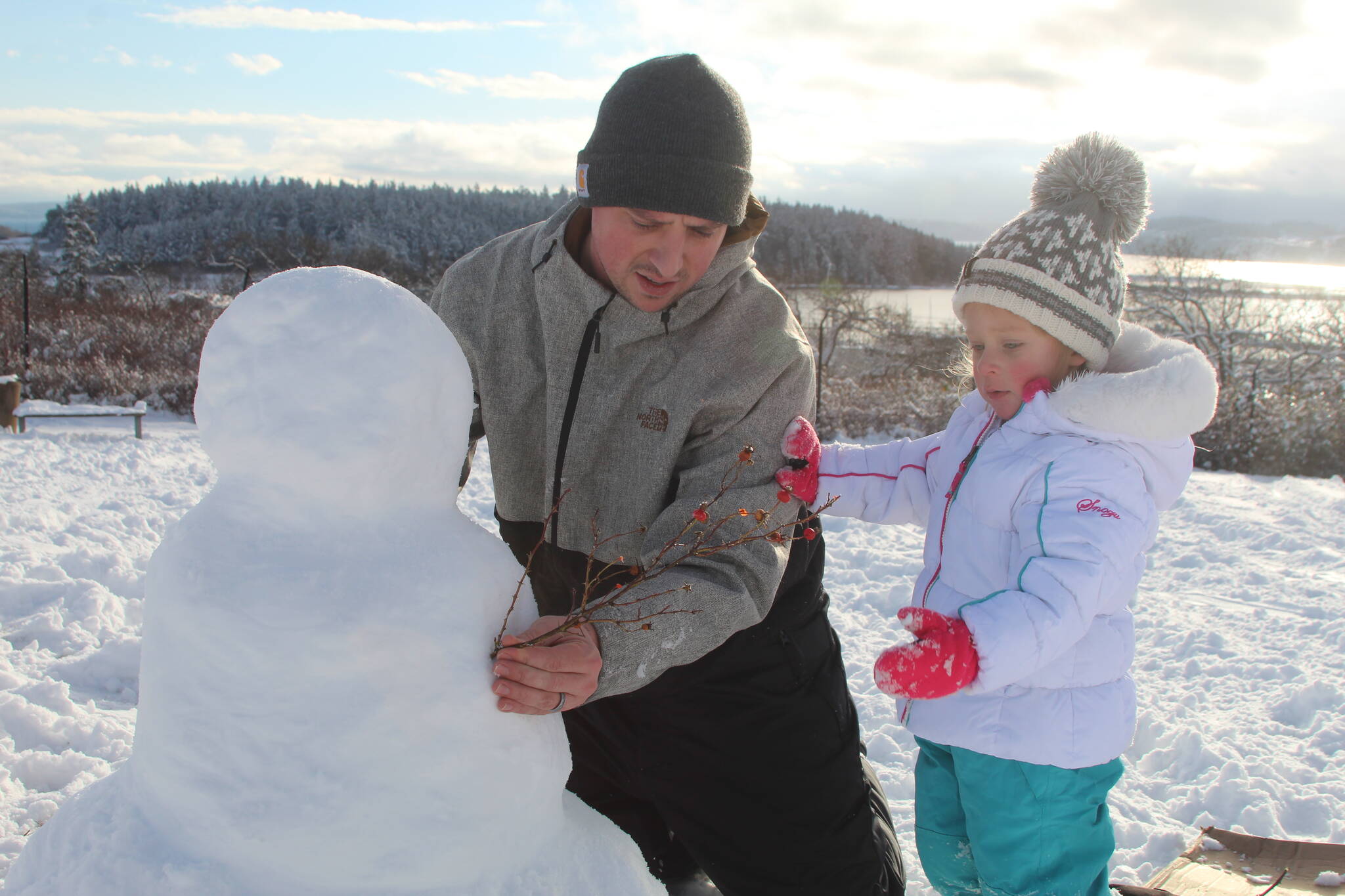 Corey Butler and his 3-year-old daughter, Tiffany, build a snowman together Tuesday afternoon in Oak Harbor. (Photo by Karina Andrew/Whidbey News-Times)