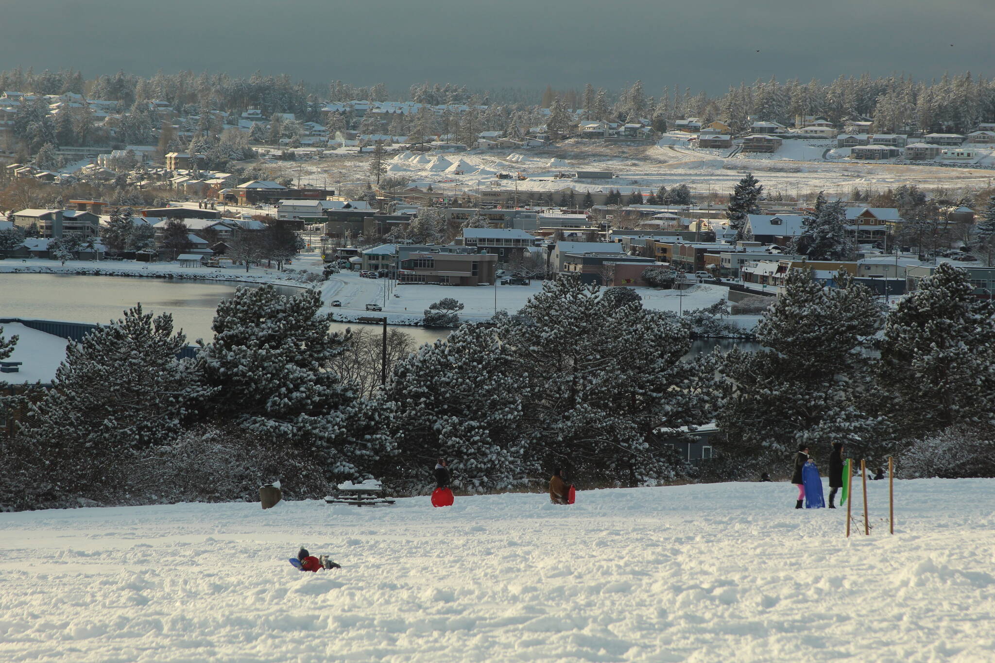 Oak Harbor residents take advantage of the first snowfall of winter by sledding on a hill overlooking the city Tuesday afternoon. (Photo by Karina Andrew/Whidbey News-Times)