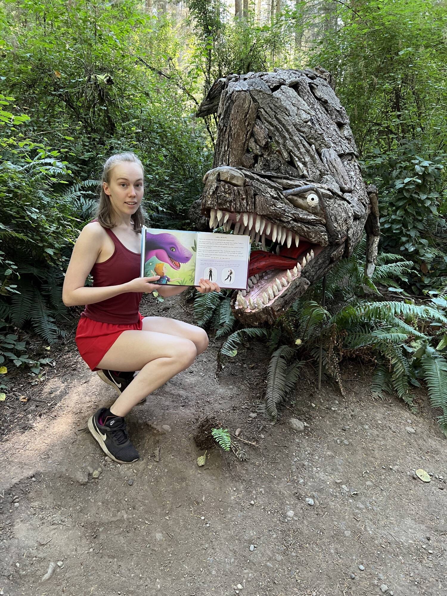 Kaelyn Lefferts with Joe Treat’s driftwood T-rex sculpture in the Price Sculpture Forest. (Photo provided)