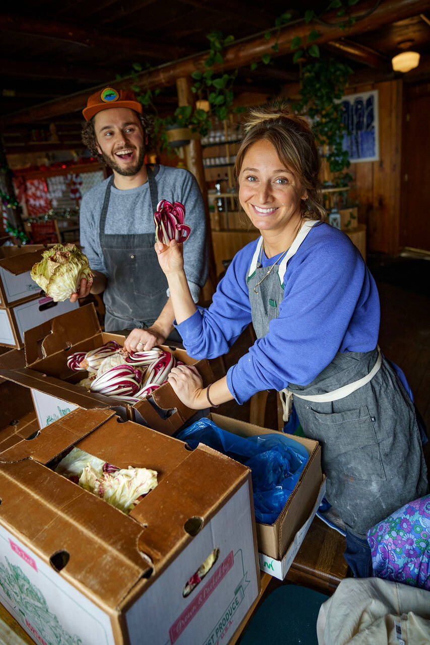 Max Dornbush and Courtney Storer unpack fresh veggies and greens from the Whidbey Island Grown Cooperative. (Photo by David Welton)
