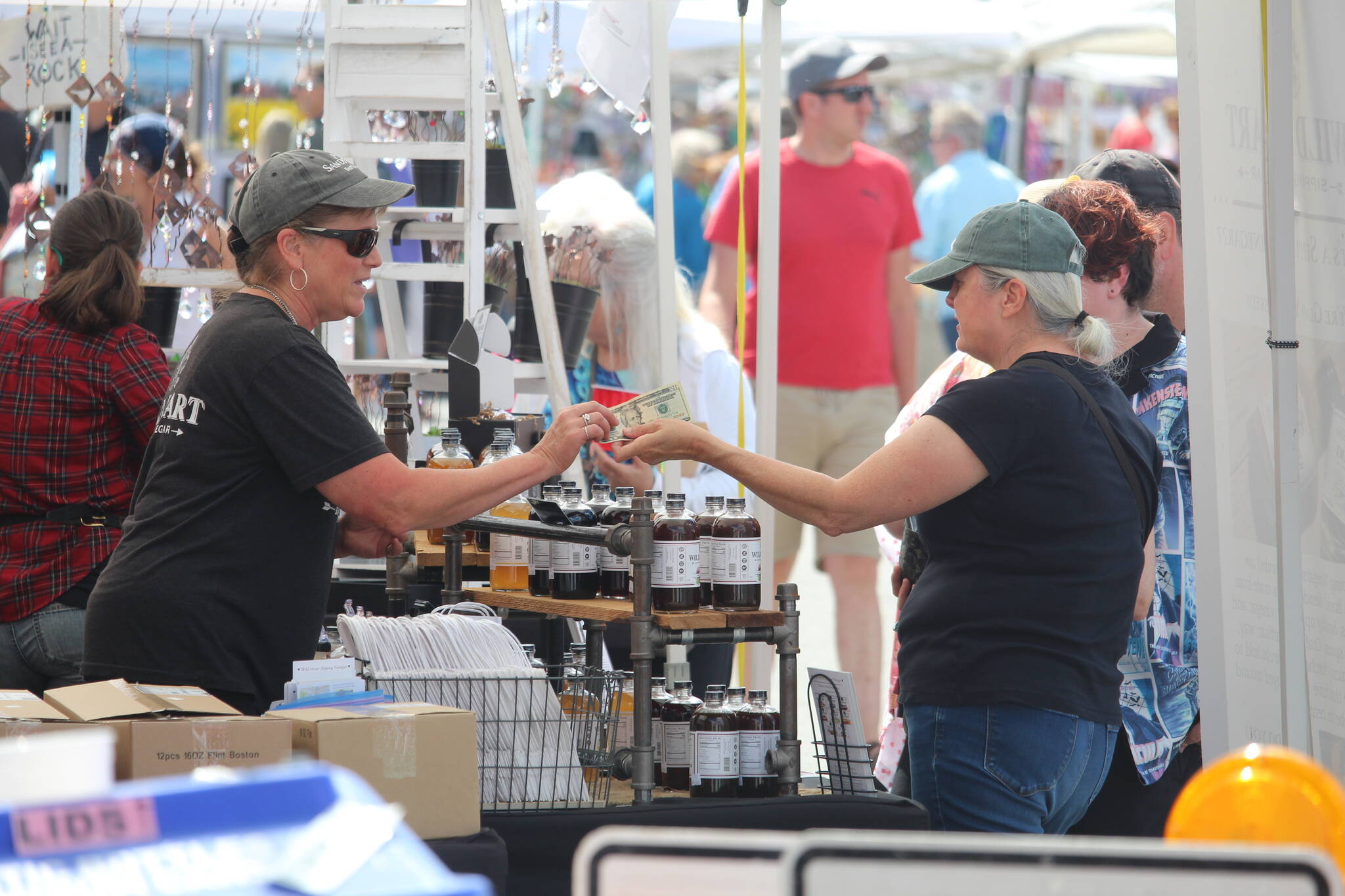 A Coupeville Arts and Crafts Festival patron purchases goods from a local vendor at the 2022 festival. (File photo by Karina Andrew/Whidbey News-Times)