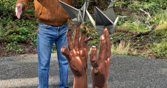 Photo provided
Scott Price, owner of Price Sculpture Forest, with the augmented reality version of the sculpture “Inciting Hope,” by artist Bill Baran-Mickle. The real-world sculpture is currently on display in Poulsbo, Washington.