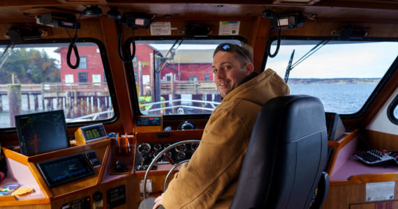 Photo by David Welton
Christopher Lewman takes the wheel of the Glacier Spirit for mussel raft tours during the Penn Cove Musselfest Sunday. The annual event, which was back at full strength, drew big crowds in Coupeville.