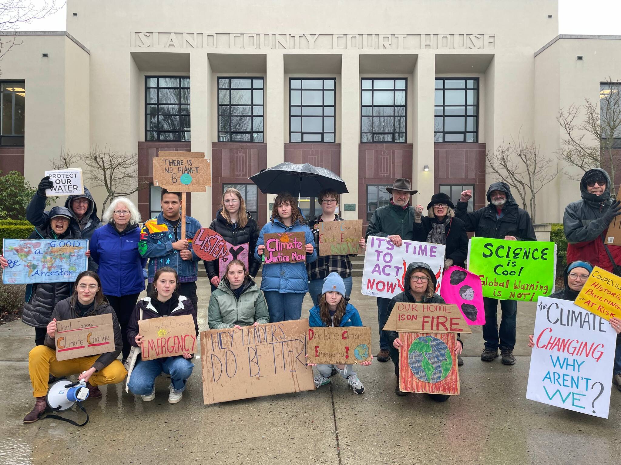 Protesters gather in front of the Island County commissioners’ offices in Coupeville March 24 in a move meant to prompt the elected officials to declare a climate emergency. (Photo provided)