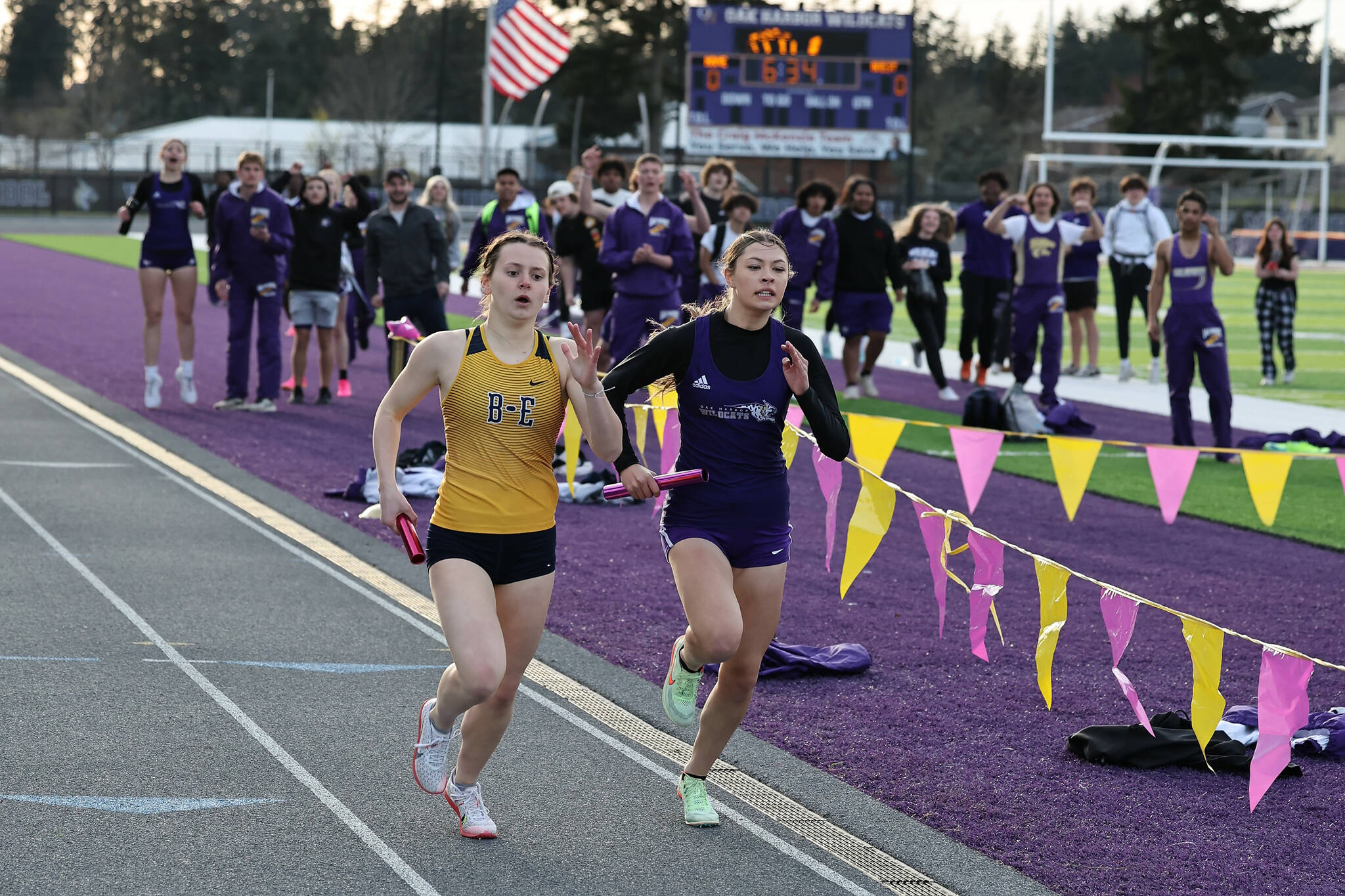 Audrey Hart (right) races a Burlington athlete. The Oak Harbor High School varsity girls team defeated Burlington 96.83 to 53.16. (Photo by John Fisken)