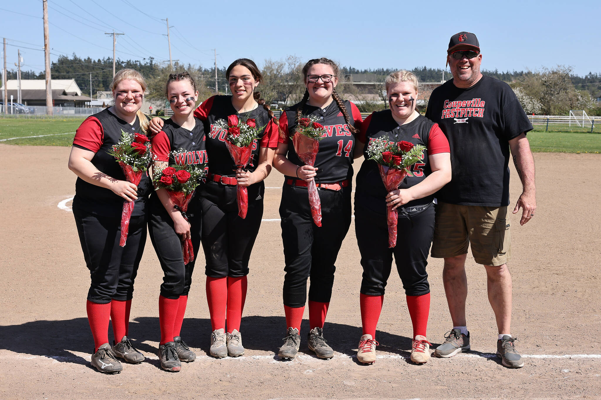 Photo by John Fisken
From left, seniors Maya Lucero, Gwen Gustafson, Melanie Navarro, Sofia Peters and Allie Lucero and Coach Kevin McGranahan celebrate senior night at a softball game against La Conner Saturday afternoon. The Wolves won 17-2.