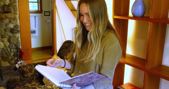 Development and Communications Specialist Nia Martin pages through a journal in one of the Hedgebrook cottages. (Photo by Kira Erickson/South Whidbey Record)