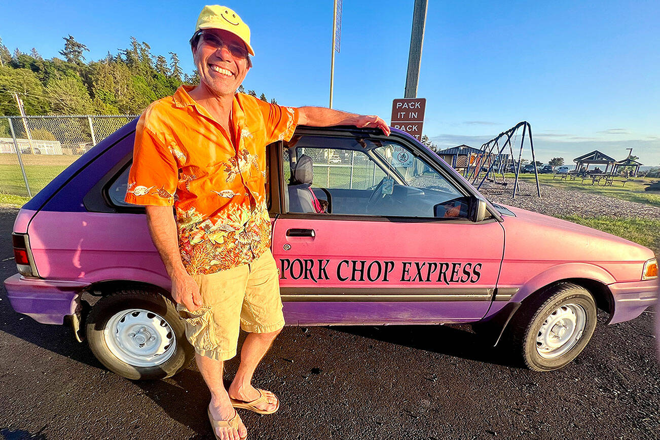 Dave "Bronco" Erickson stands next to the pink-and-purple 1991 Subaru Justy hatchback “Pork Chop Express” car that he is seeking to re-home for $500. The car has been on Whidbey Island for years, mainly as yard art. (Andrea Brown / The Herald)