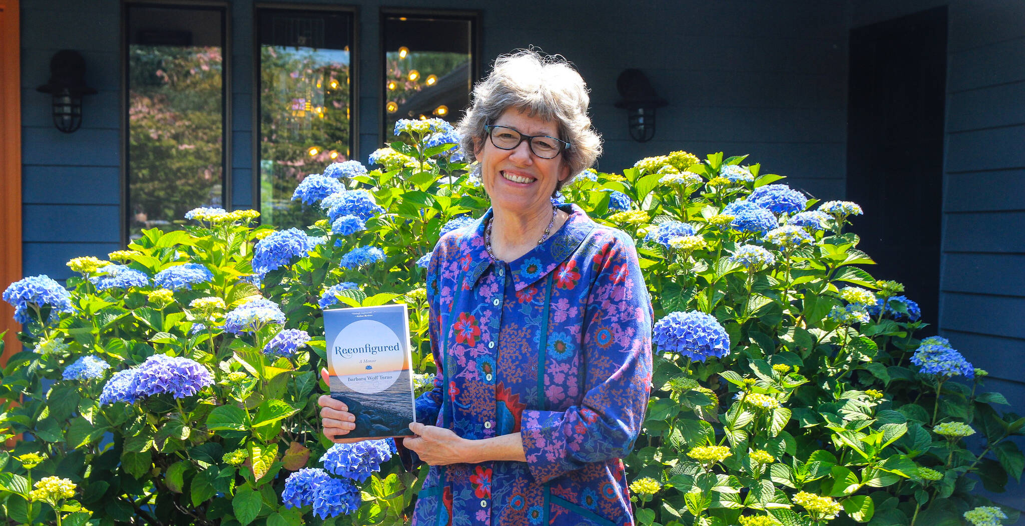 Barbara Wolf Terao holds her memoir, Reconfigured, in front of her house in Freeland. (Photo by Luisa Loi)