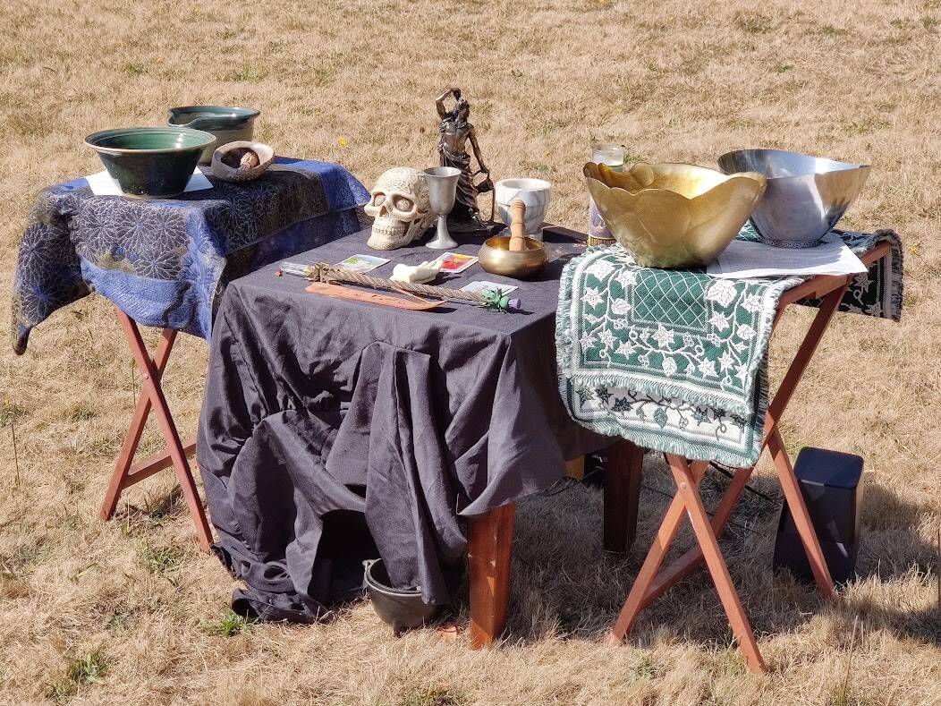 A communal altar displaying, among different things, a statuette of Dionysus, a decorated skull to remember death, a chalice and three tarot cards divining the past, present and future. The altar represents different Pagan beliefs. (Photo by Aaron Taggert)