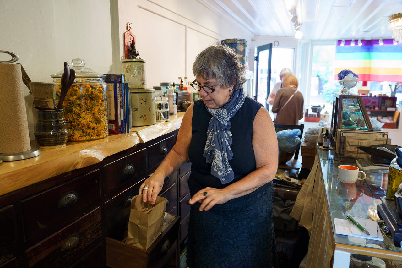 Karyn Schwartz pulls some herbs from an antique set of drawers within her apothecary. (Photo by David Welton)