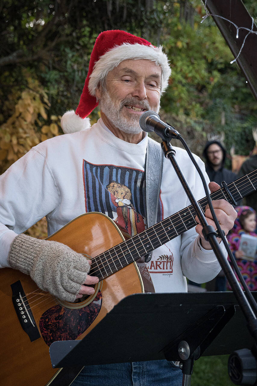 Karl Olsen plays the guitar and leads the gathered crowd in some carols. (Photo by David Welton)