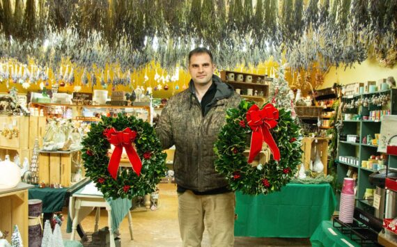 Photo by Luisa Loi
Isaiah Rawl, greens manager at A Knot in Thyme, poses with some freshly made wreaths inside of the gift shop.