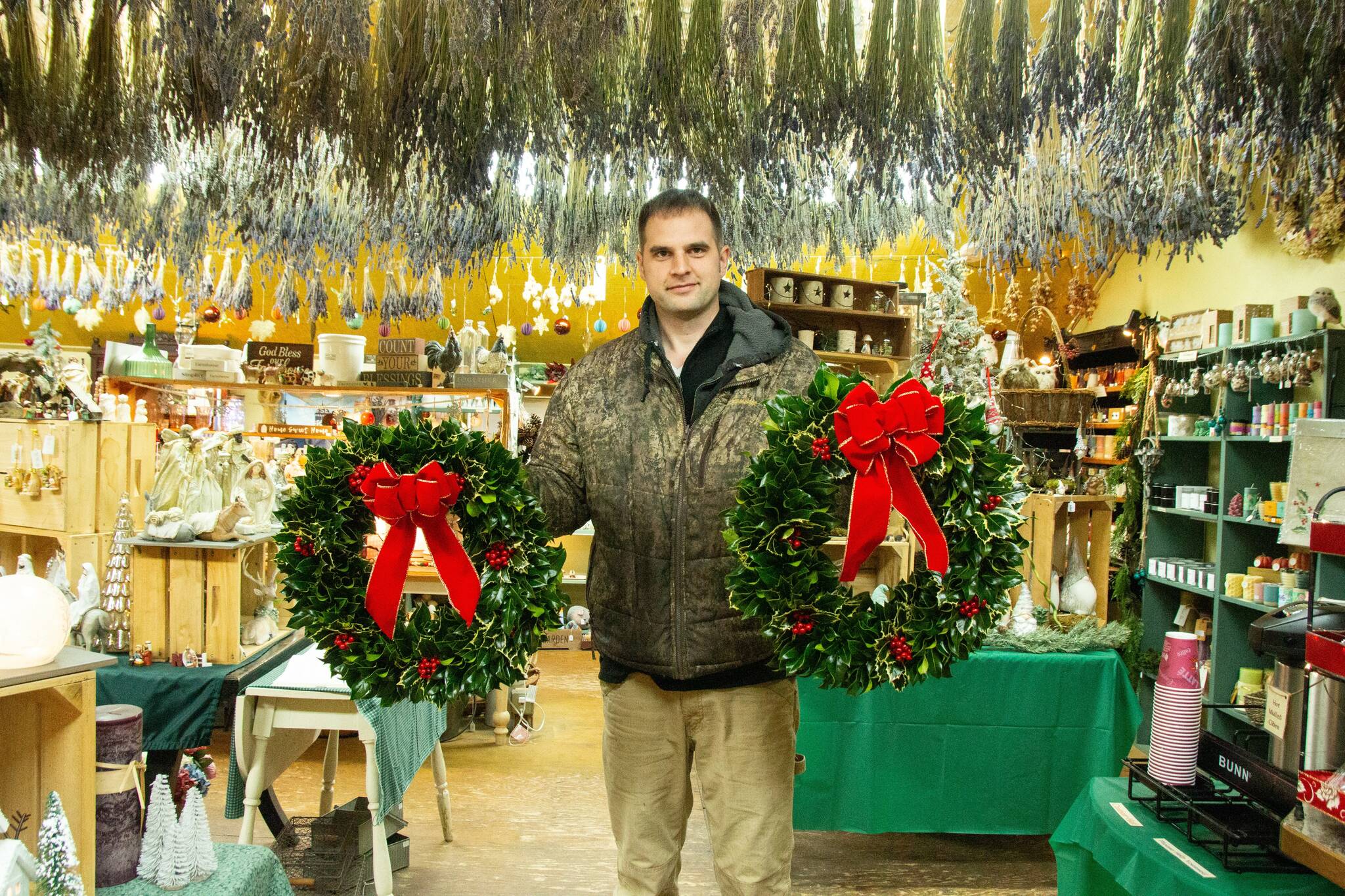 Isaiah Rawl, greens manager at A Knot in Thyme, poses with some freshly made wreaths inside of the gift shop. (Photo by Luisa Loi)