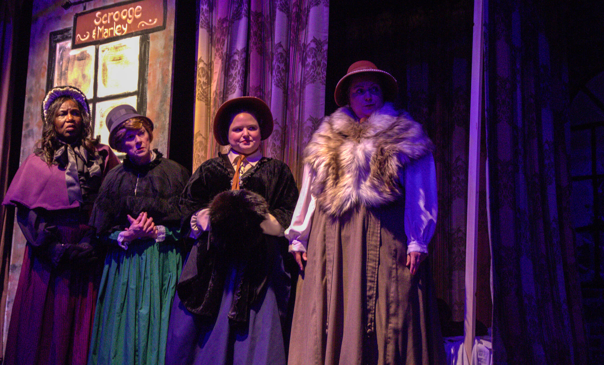 The four madrigals (played by Allenda Jenkins, Geri Thomas, Ellie Alexander and Susan Larsen) watch Scrooge act unpleasantly. (Photo by Luisa Loi)
