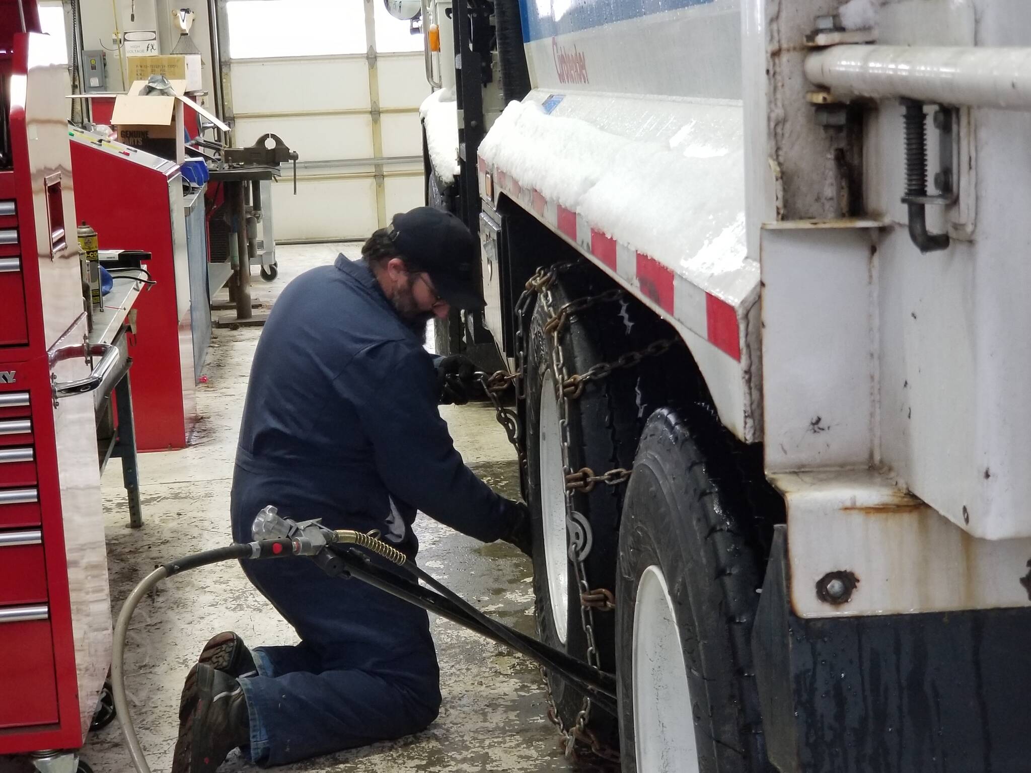 On January 18, 2024, Public Works Department mechanic Joe Ramirez installs chains on the tires of the City’s garbage trucks during a snowstorm. (Photo courtesy of City of Oak Harbor Public Works)