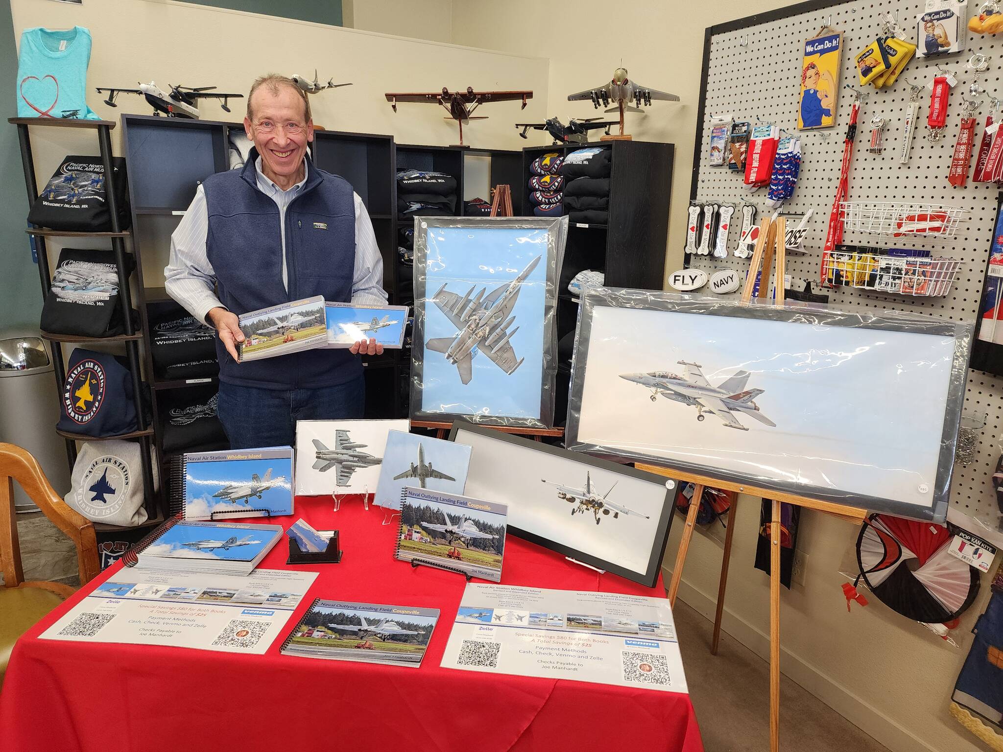 Photographer Joe Manhardt poses at his booth at the book launch of “Naval Air Station Whidbey Island” at Pacific Northwest Naval Air Museum on Saturday. (Photo courtesy of Pacific Northwest Naval Air Museum)
