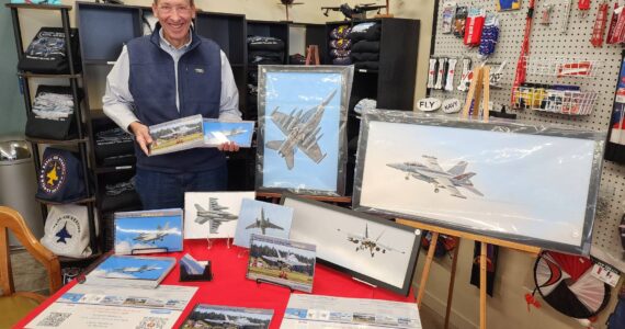 Photographer Joe Manhardt poses at his booth at the book launch of "Naval Air Station Whidbey Island" at Pacific Northwest Naval Air Museum on Saturday. (Photo courtesy of Pacific Northwest Naval Air Museum)