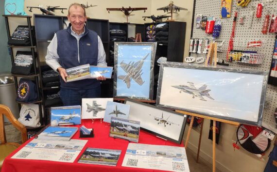 Photographer Joe Manhardt poses at his booth at the book launch of "Naval Air Station Whidbey Island" at Pacific Northwest Naval Air Museum on Saturday. (Photo courtesy of Pacific Northwest Naval Air Museum)