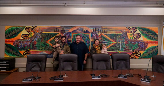 From left to right: George Mann, artist Nick Mann, Mayor Ronnie Wright, artist Kendall Mann and Anastasia Mann pose before the newly-installed "Song of the Salish Sea" in council chambers. (Photo by Sam Fletcher)