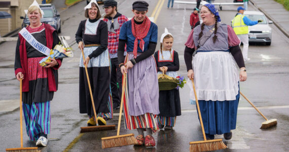 Photos by David Welton
Holland Happening Grand Marshal Audrey Butler Henry Vanden Haak and other Dutch sweepers parade their klompen shoes in Downtown Oak Harbor. The cold, the rain and mild wind did not stop the festivities, which featured a professional wooden shoe carver, the annual Klompen Canal Race, delft tiles and numerous vendors.