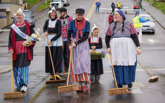 Photos by David Welton
Holland Happening Grand Marshal Audrey Butler Henry Vanden Haak and other Dutch sweepers parade their klompen shoes in Downtown Oak Harbor. The cold, the rain and mild wind did not stop the festivities, which featured a professional wooden shoe carver, the annual Klompen Canal Race, delft tiles and numerous vendors.