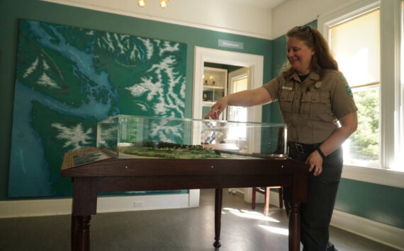 Interpretive specialist Jen Gray interacts with a Fort Casey map in the new Admiralty Head Lighthouse exhibit. (Photo by Sam Fletcher)