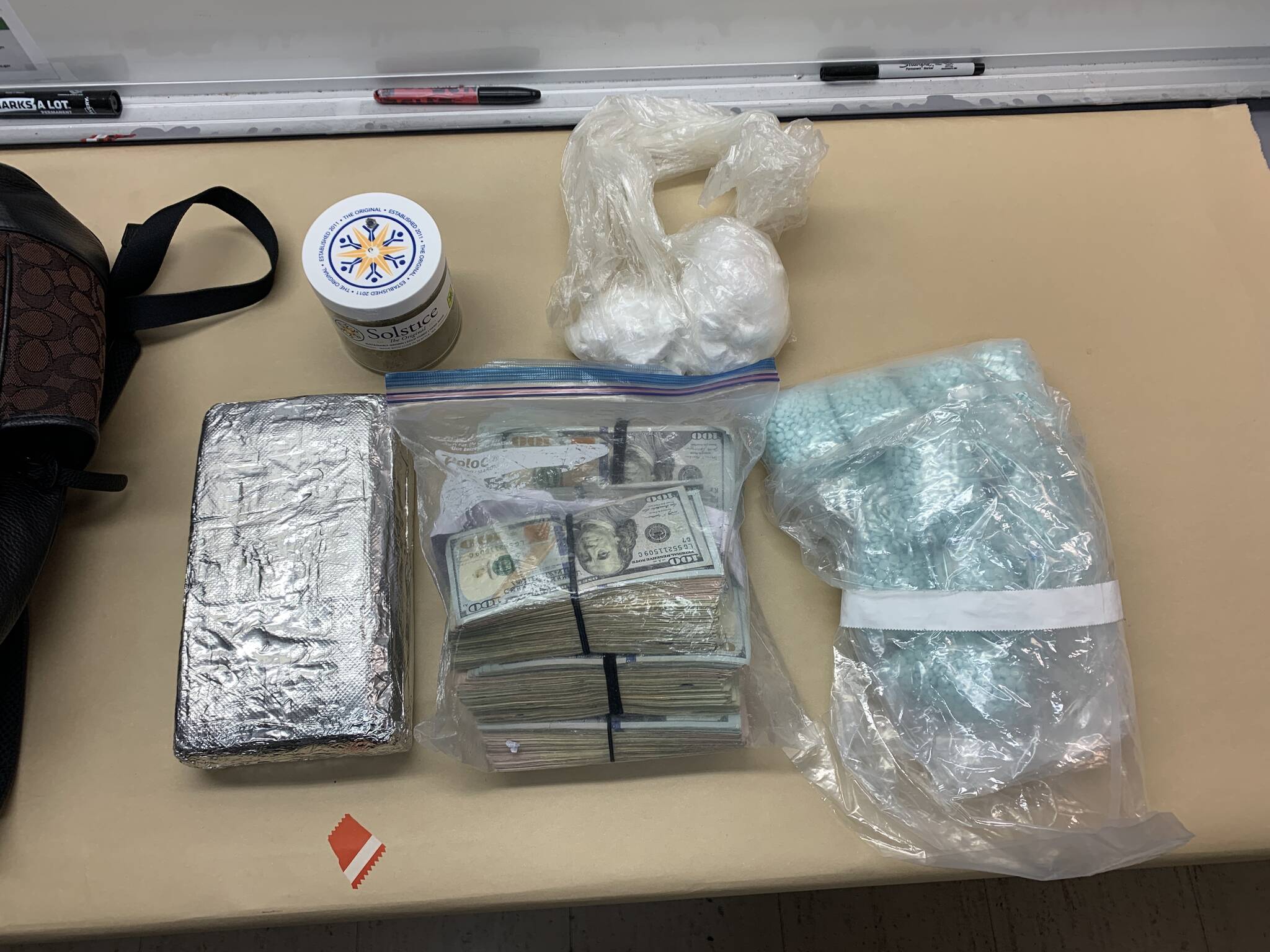 An Oak Harbor police photo shows plastic bags of suspected cocaine, a foil-covered brick of suspected cocaine, $79,000 in cash and large number blue M30 pills.