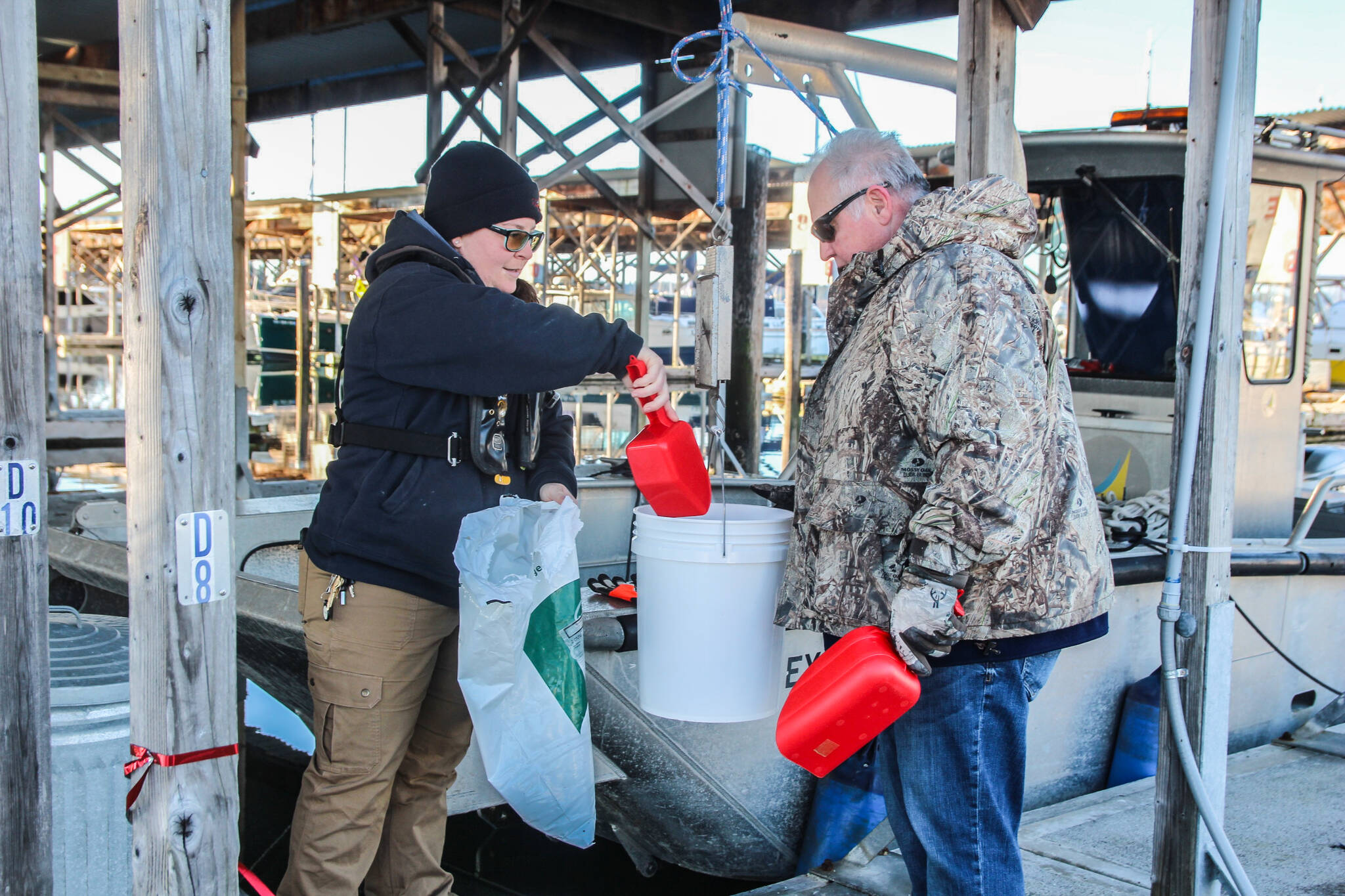 (Photo by Luisa Loi)
At left, Alyce Henry and Tracy Loescher fill their buckets with salmon feed.