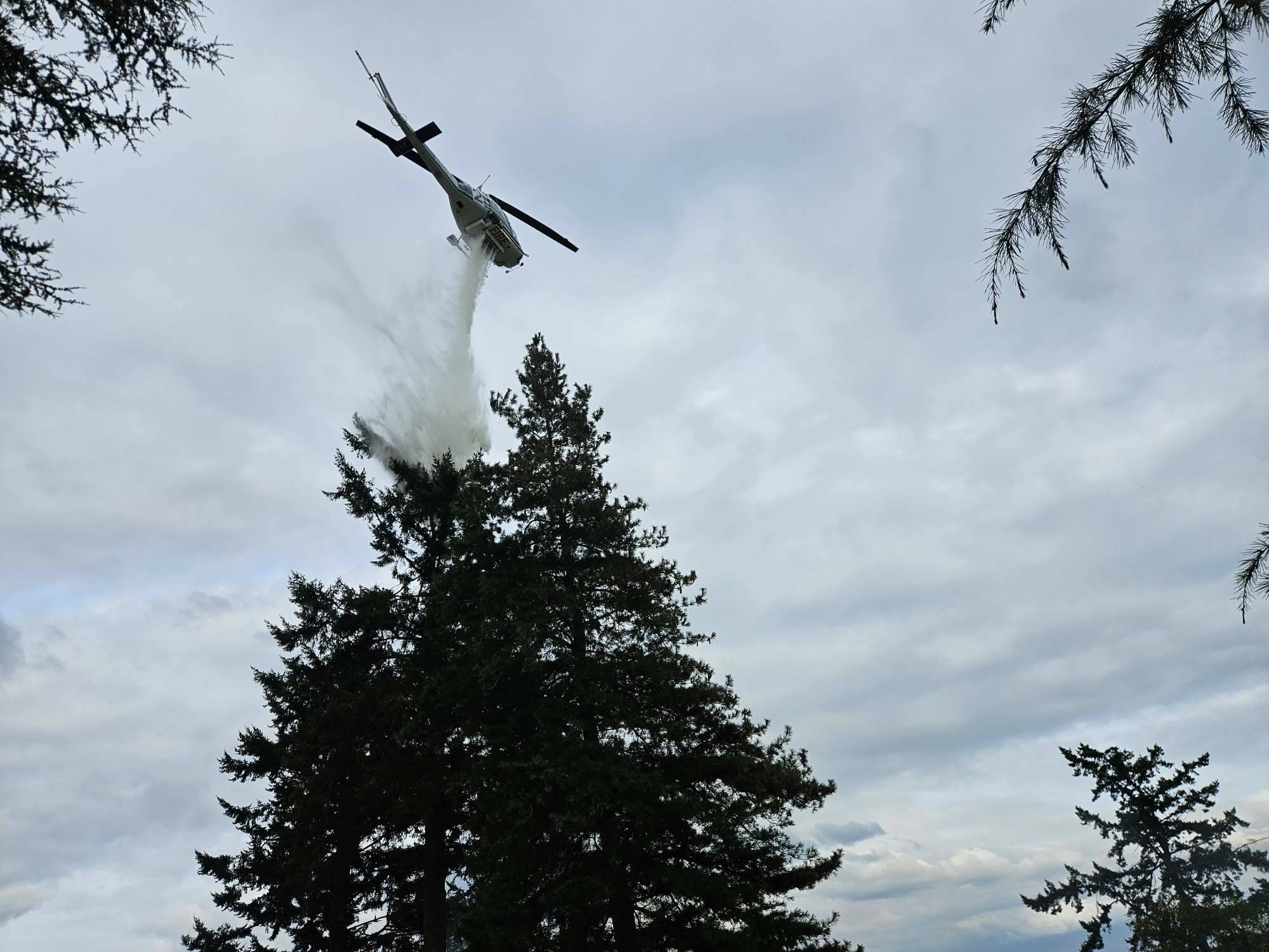 (Photo by South Whidbey Fire/EMS) A Department of Natural Resources helicopter responded to the fire, pouring down water from above.
