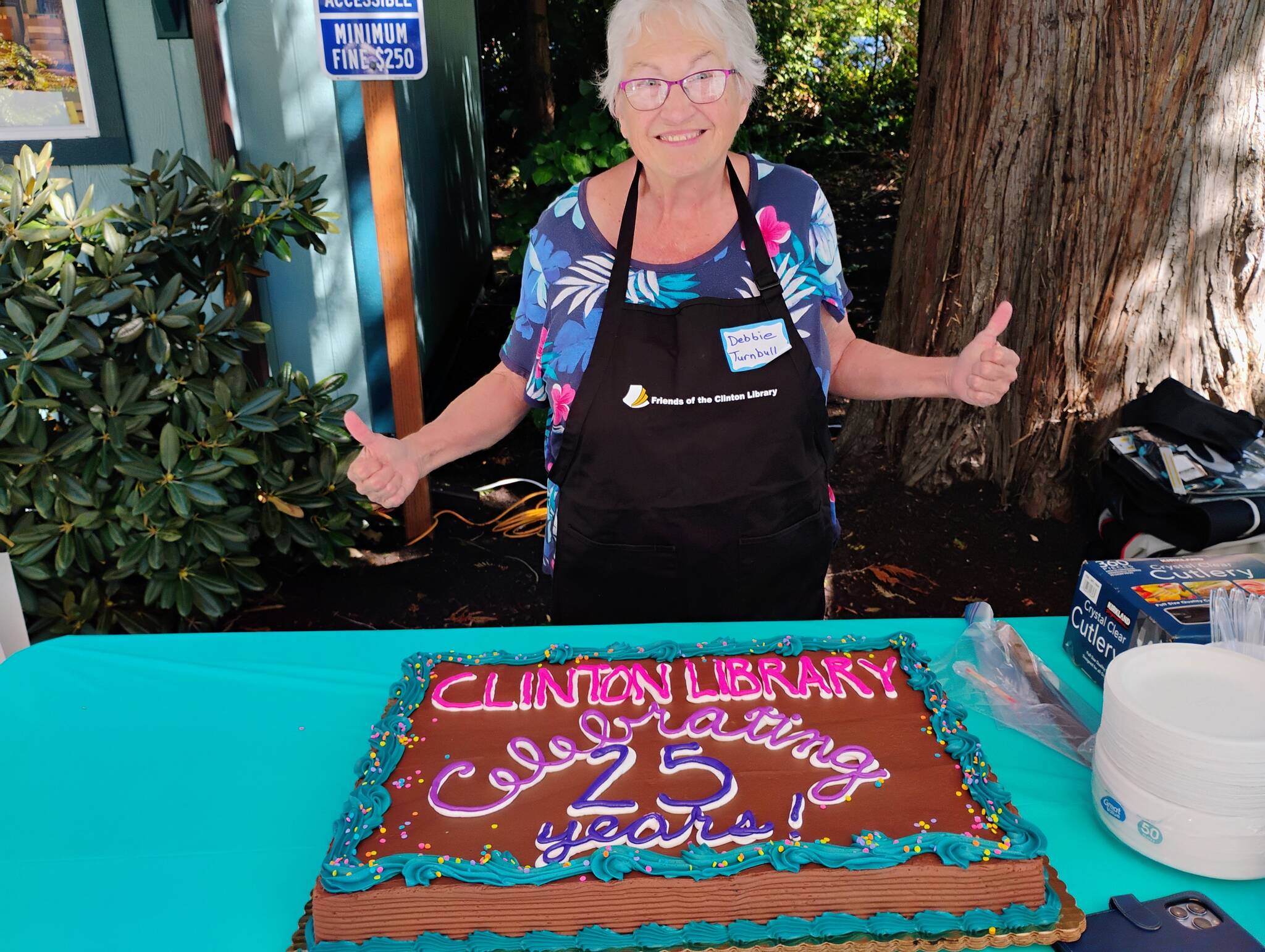 (Photo provided) Debbie Turnbull smiles, ready to cut in to the Clinton Librarys custom, festive anniversary cake.