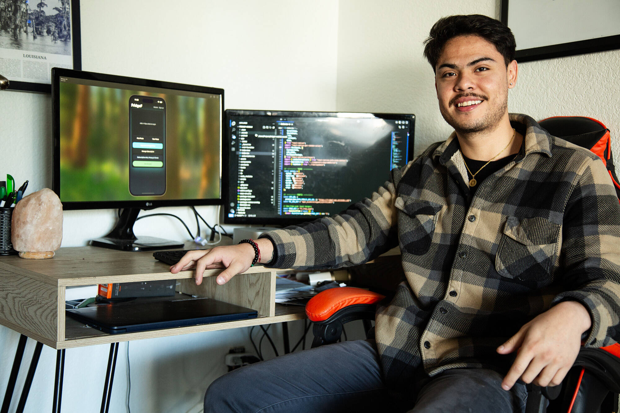 Luis Ortiz Orantes smiles in front of his workstation in his apartment, where he coded the app. (Photo provided.)