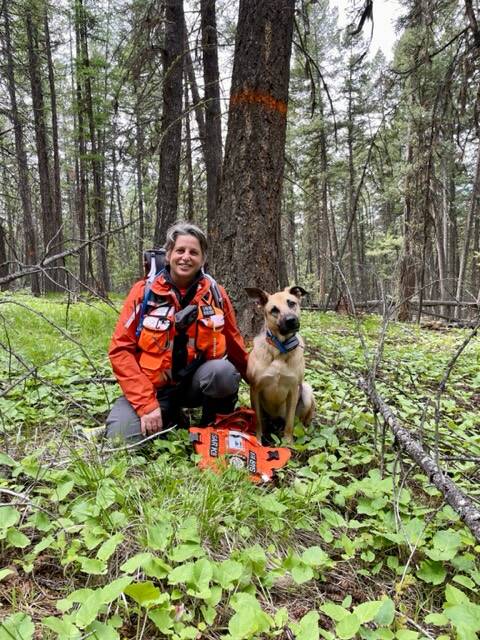 Alli Paul poses in the woods with her shepherd mix, Stella, after getting certified for K9 Search and Rescue.