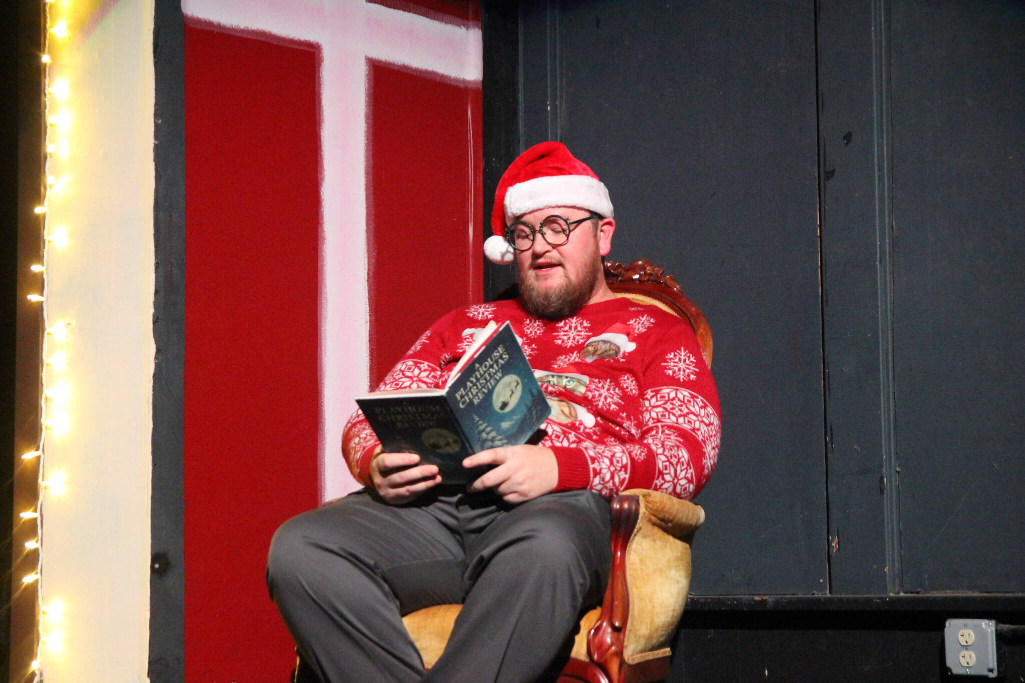 Co-director Eric George dons a Christmas hat and a not-so-ugly Christmas sweater covered in cats. He reads from a custom Christmas Playhouse book, introducing each act.